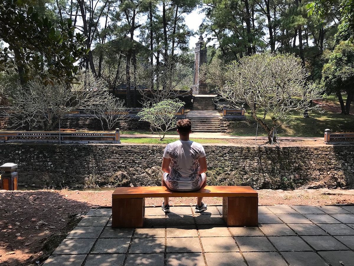 Man sitting on a bench in the grounds of the Tu Duc tomb Hue