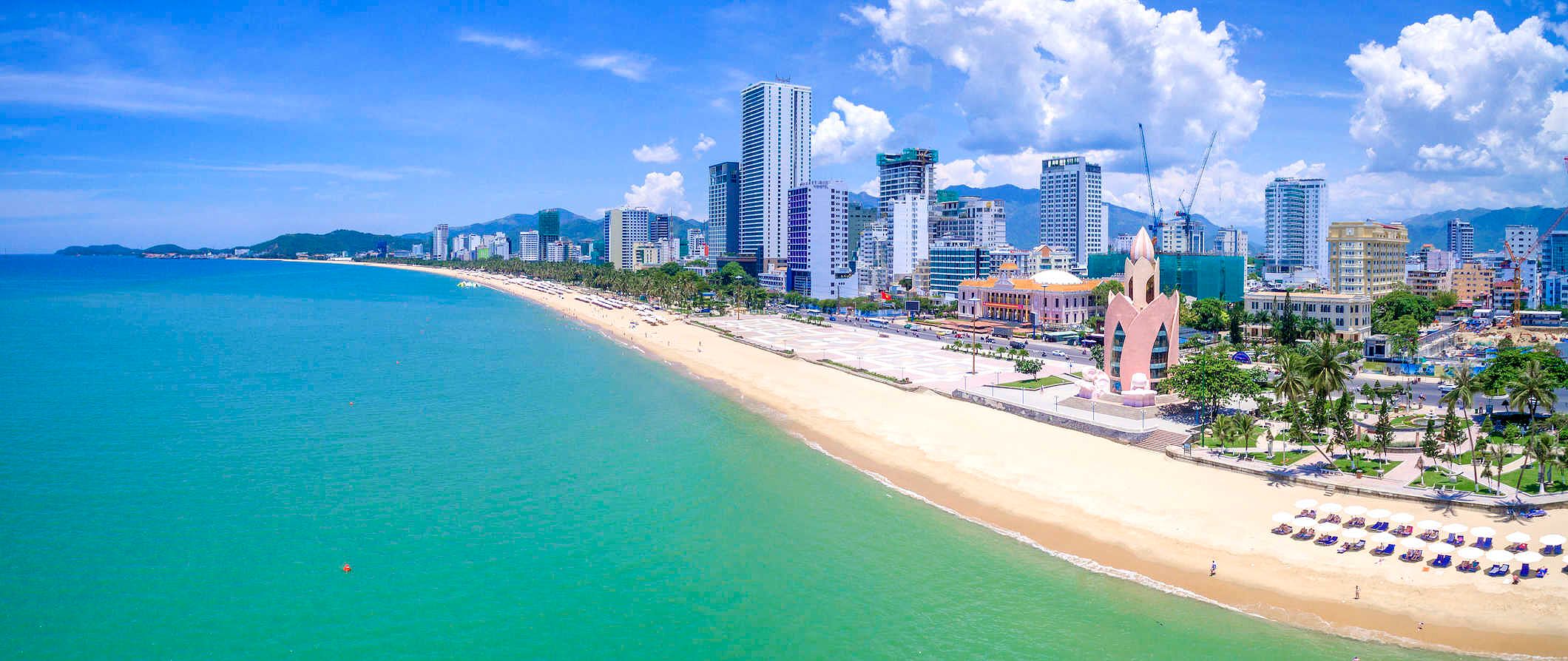 The beach scene along the coats of Nha Trang, Vietnam with the city skyline towering along the coastline